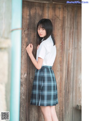 A young woman leaning against a wooden door.
